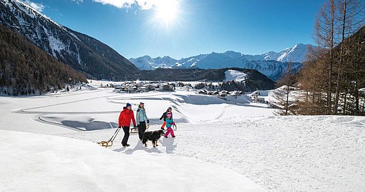 Familie beim Spaziergang mit der Rodel