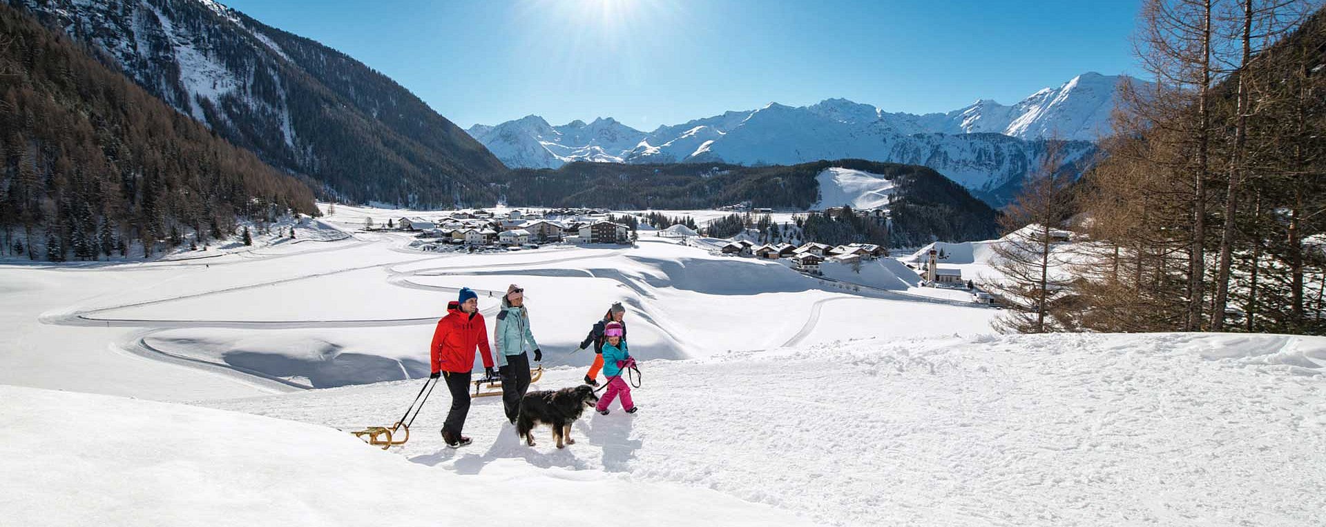 Familie beim Spaziergang mit der Rodel